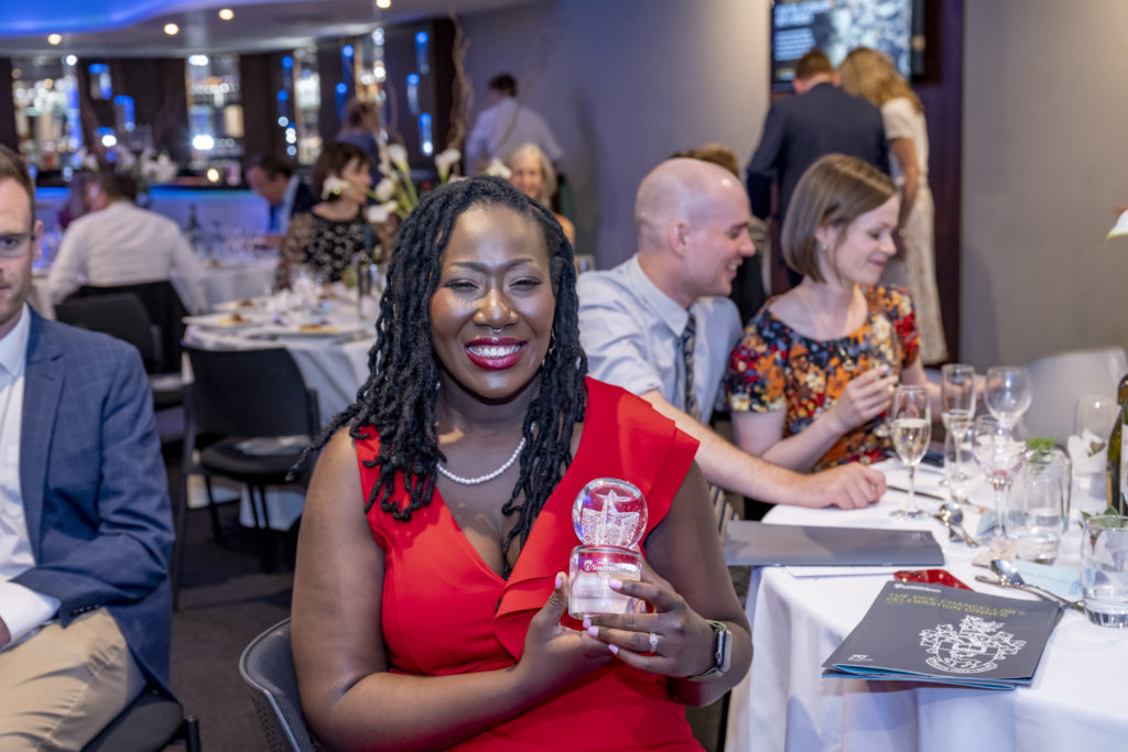 Dr Kizanne James-McCarthy sitting at the dinner table holding her Rising Star Award