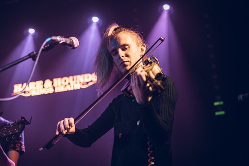 Alex Garden playing the fiddle onstage under spotlights.