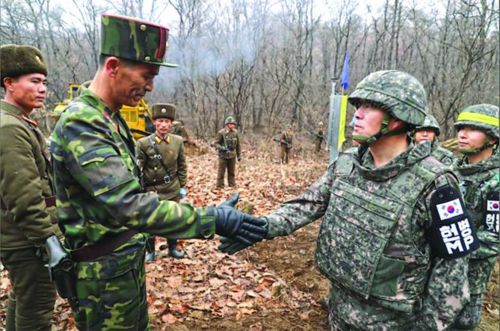 A South Korean soldier shaking the hand of his North Korean counterpart.